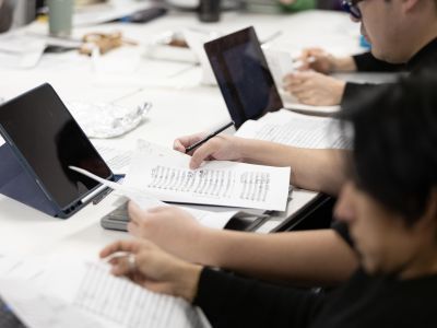 participants in classroom with manuscript paper and tablet in front of them on desk
